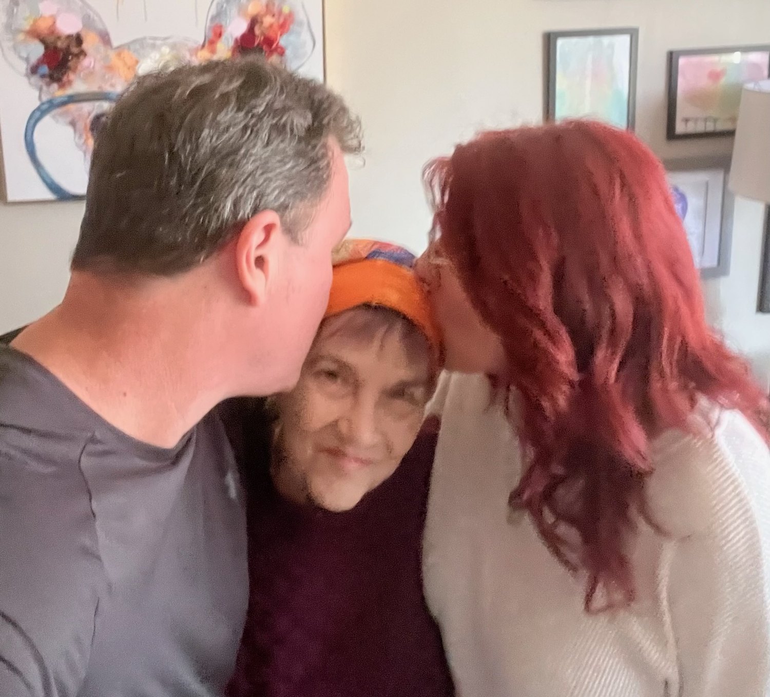 Karen and Tom, one on each side, kissing their mother on the top of her head.